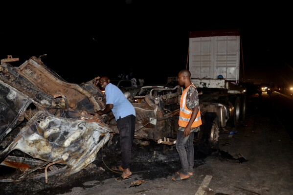 Rescue workers remove the trailer that crashed into halted vehicles and burst into flames in Abuja, Nigeria, Wednesday , March 19, 2025. (AP Photo/Olamikan Gbemiga)