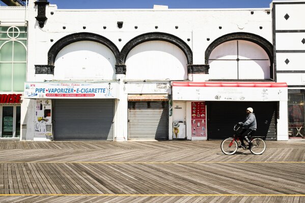 A cyclist rides past shuttered businesses during the coronavirus outbreak on the boardwalk in Atlantic City, N.J., Tuesday, April 28, 2020. (AP Photo/Matt Rourke)