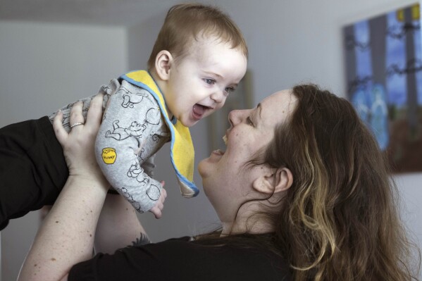 Nicole Slemp, a new mother of seven-month-old William, lifts up her son in their home, Thursday, March 14, 2024 in Auburn, Wash.. Slemp recently quit her job because she and her husband couldn't find child care they could afford. Expensive, scarce child care is putting Puget Sound parents out of work. (Ellen M. Banner/The Seattle Times via AP)
