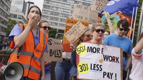 Members of the Unite union stand on the picket line outside Guys and St Thomas' Hospital during a 24 hour strike in their continued dispute over pay, in London, Thursday July 13, 2023. (Lucy North/PA via AP)