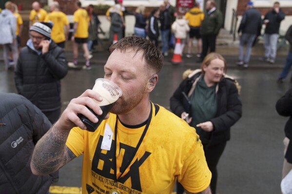 Contestant Brett Guilfoyle drinks a beer after competing in the World Coal Carrying Championships, where contestants carry a 50 kg bag of coal for just over a kilometre, in Ossett, West Yorkshire, England, Monday, April 21, 2025. (AP Photo/Jon Super)