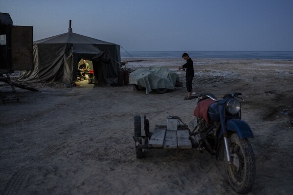 Men work in a yurt camp by the dried-up Aral Sea, outside Muynak, Uzbekistan, Sunday, June 25, 2023. (AP Photo/Ebrahim Noroozi)