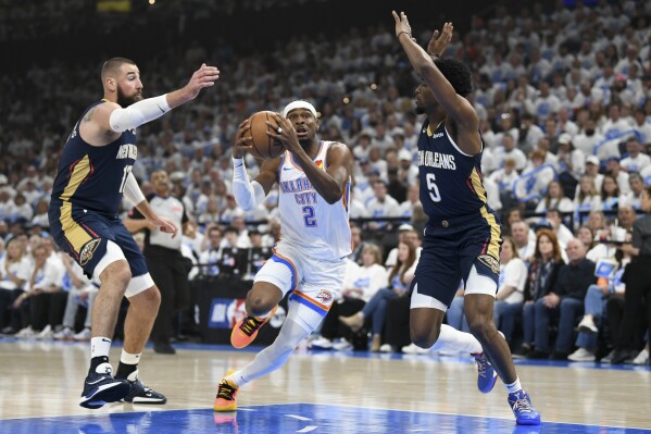 Oklahoma City Thunder guard Shai Gilgeous-Alexander (2) drives past New Orleans Pelicans center Jonas Valanciunas, left, and forward Herbert Jones (5) in the first half of Game 1 of an NBA basketball first-round playoff series, Sunday, April 21, 2024, in Oklahoma City. (AP Photo/Kyle Phillips)
