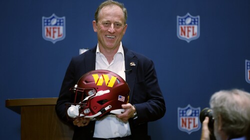 Josh Harris, leader of a group buying the Washington Commanders, poses with a team helmet after NFL owners voted to approve the sale in Bloomington, Minn., Thursday, July 20, 2023. (AP Photo/Bruce Kluckhohn)