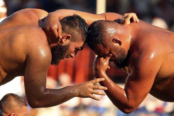 Wrestlers, doused in olive oil, compete during the 660th instalment of the annual Historic Kirkpinar Oil Wrestling championship, in Edirne, northwestern Turkey, Saturday, July 10, 2021.Thousands of Turkish wrestling fans flocked to the country's Greek border province to watch the championship of the sport that dates to the 14th century, after last year's contest was cancelled due to the coronavirus pandemic. The festival, one of the world's oldest wrestling events, was listed as an intangible cultural heritage event by UNESCO in 2010. (AP Photo/Emrah Gurel)