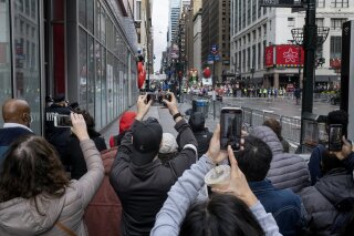 People attempt to take photos as the last floats that are part of the modified Macy's Thanksgiving Day Parade move away in New York, Thursday, Nov. 26, 2020. Due to the pandemic, crowds of onlookers were not allowed to attend the annual parade. (AP Photo/Craig Ruttle)