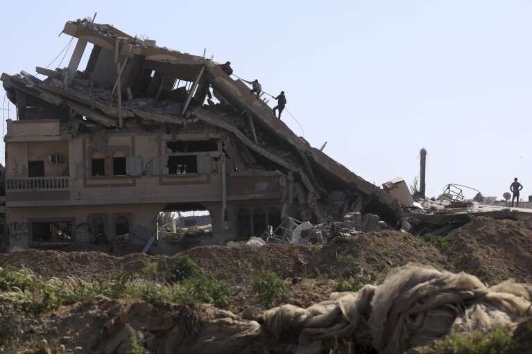 فلسطينيون يتفقدون الدمار الذي خلفه الهجوم الجوي والبري الإسرائيلي بعد انسحابهم من خان يونس، جنوب قطاع غزة، الأحد، 7 أبريل، 2024. (AP Photo/Ismael Abu Dayyah)
