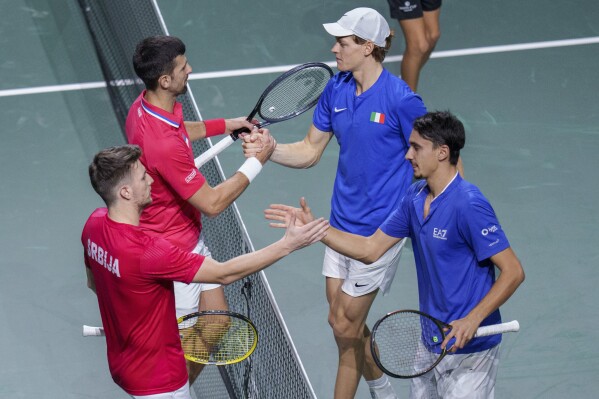 Italy's Jannik Sinner, top right, and his teammate Lorenzo Sonego shake hand after winning with Serbia's Novak Djokovic and Miomir Kecmanovic during a Davis Cup semi-final doubles tennis match between Italy and Serbia in Malaga, Spain, Saturday, Nov. 25, 2023. (AP Photo/Manu Fernandez)