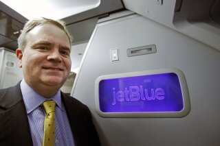 FILE - In this Feb. 5, 2015, file photo, JetBlue's incoming CEO Robin Hayes pauses in front of a JetBlue logo inside an Airbus A321 aircraft at JFK airport in New York. Airlines are starting to see a slight rise in bookings, but air travel remains down about 90%, prompting speculation about which carriers might go under. Hayes admits he doesn’t know how quickly air travel will recover from the coronavirus outbreak, and no matter what, his will be a smaller airline. Hayes, however, is confident that all large airlines in the U.S. will survive. (AP Photo/Kathy Willens, File)