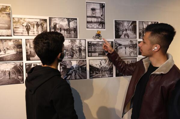 Visitors look on a photo exhibition "Albania from my Eyes" at the National Gallery of Arts in Tirana, Albania, on Monday, Jan. 31, 2022. Afghan evacuees in Albania opened a photo exhibition on their impressions on the tiny Western Balkan country. (AP Photo/Franc Zhurda)