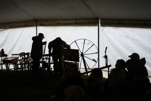 Attendees inspect antiques that will go up for auction during the 56th annual mud sale to benefit the local fire department in Gordonville, Pa., Saturday, March 9, 2024. Mud sales are a relatively new tradition in the heart of Pennsylvania's Amish country, going back about 60 years and held in early spring as the ground begins to thaw but it's too early for much farm work. (AP Photo/Matt Rourke)