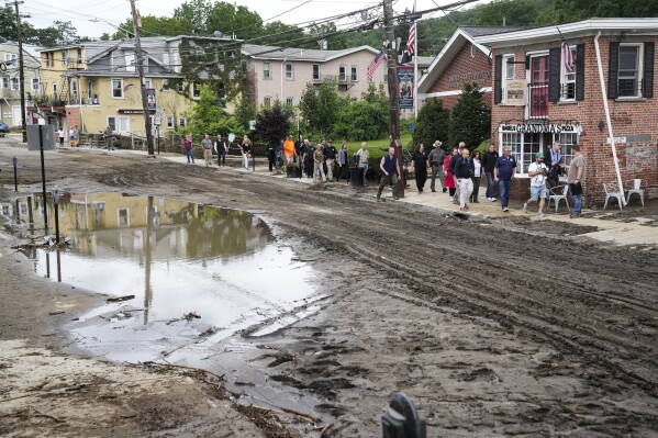 FILE - New York Gov. Kathy Hochul and a group of emergency workers and journalists pass along Main Street, July 10, 2023, in Highland Falls, N.Y., following heavy rain. New York Gov. Kathy Hochul has signed a bill Friday, Sept. 22, 2023, requiring people selling their homes to disclose whether their properties have been flooded or are at risk for future flooding. (AP Photo/John Minchillo, File)