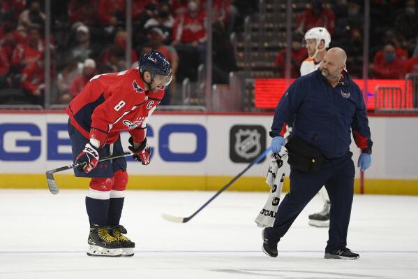 Washington Capitals left wing Alex Ovechkin (8) skates toward the bench next to a trainer after he was injured during the first period of the team's NHL preseason hockey game against the Philadelphia Flyers, Friday, Oct. 8, 2021, in Washington. (AP Photo/Nick Wass)