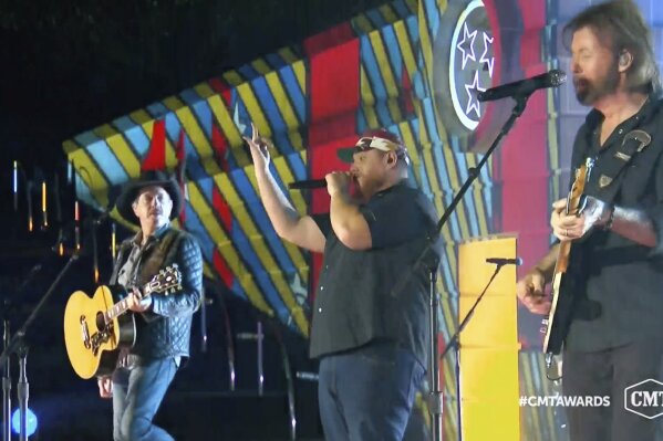 In this video image provided by CMT, Kix Brooks, from left, Luke Combs and Ronnie Dunn perform "1, 2 Many” during the Country Music Television awards airing on Wednesday Oct. 21, 2020. (CMT via AP)