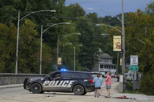 A police car blocks a bridge crossing the Pigeon River in Newport, Tenn., Saturday, Sept. 28, 2024. Tropical depression Helene brought flooding to the area on Friday. (AP Photo/George Walker IV)