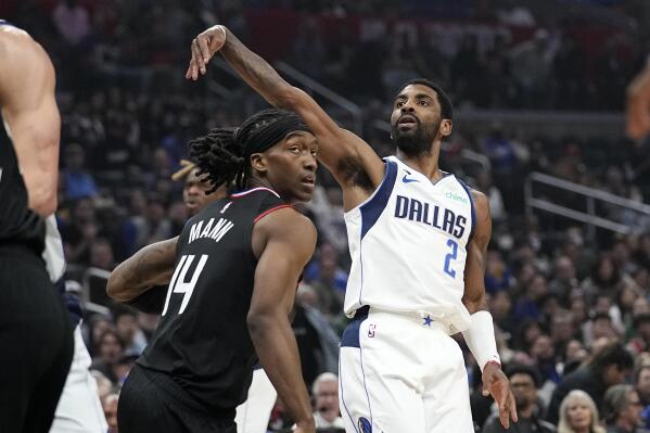 Dallas Mavericks guard Kyrie Irving, right, follows through after shooting as Los Angeles Clippers guard Terance Mann defends during the first half of an NBA basketball game Wednesday, Feb. 8, 2023, in Los Angeles. (AP Photo/Mark J. Terrill)