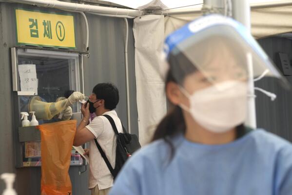 A medical worker in a booth takes a nasal sample from a man during coronavirus testing at a makeshift testing site in Seoul, South Korea, Thursday, July 22, 2021. South Korea is reporting 1,842 newly confirmed coronavirus cases for the previous 24 hours - setting a new pandemic single-day record for the second straight day. (AP Photo/Ahn Young-joon)