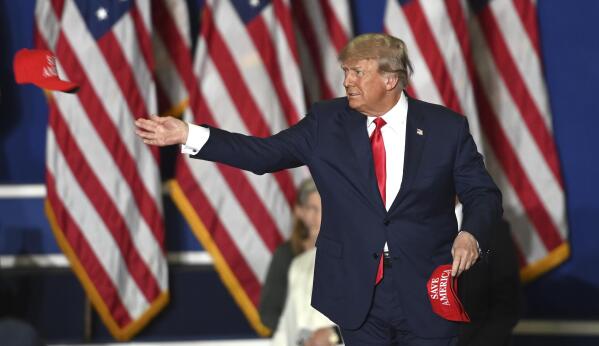 Former President Donald Trump tosses caps to the crowd as he steps onstage during a rally at the Macomb Community College Sports & Expo Center in Warren, Mich., Saturday, Oct. 1, 2022. (Todd McInturf/Detroit News via AP)