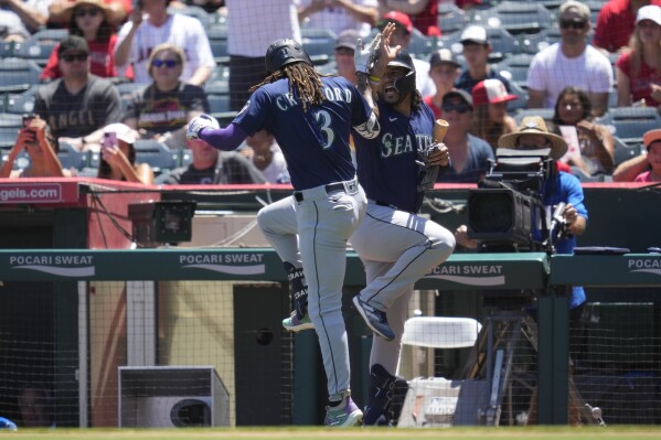 Seattle Mariners' J.P. Crawford (3) celebrates with Eugenio Suarez after hitting a home run during the first inning of a baseball game against the Los Angeles Angels in Anaheim, Calif., Sunday, Aug. 6, 2023. (AP Photo/Ashley Landis)