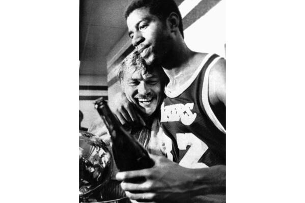 FILE - Los Angeles Lakers Earvin "Magic" Johnson hugs team owner Jerry Buss in the locker room after they won the 1980 NBA championship against the Philadelphia 76ers in Philadelphia on May 16, 1980. Johnson stepped in and played center for the injured Kareem Abdul-Jabbar in Game 6 of the NBA Finals with his Los Angeles Lakers holding a 3-2 series lead over the Philadelphia 76ers.(AP Photo/Gene Puskar, File)