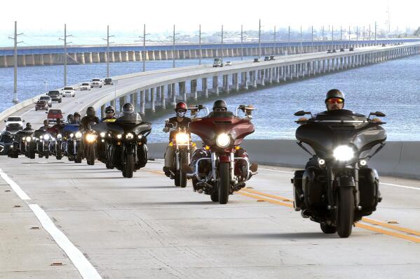 In this photo provided by the Florida Keys News Bureau, retired military veterans ride motorcycles on the Florida Keys Overseas Highway's Seven Mile Bridge Thursday, Oct. 14, 2021, near Marathon, Fla. The vets are participating in a Wounded Warrior Project event called Rolling Project Odyssey designed as therapy for emotional and mental rehabilitation for those suffering from post-traumatic stress disorder. The five-day event through the Keys, that included an interaction session with marine mammals at Dolphin Research Center on Thursday, is to end Friday, Oct. 15. (Steve Panariello/Florida Keys News Bureau via AP)