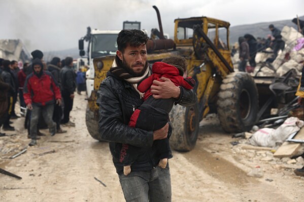 A man carries the body of an earthquake victim in the Besnia village near the Turkish border, Idlib province, Syria, Monday, Feb. 6, 2023. (AP Photo/Ghaith Alsayed, File)