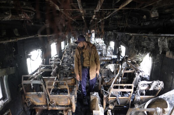 A security officer inspects the damage inside a passenger train that caught fire, killing four people in Dhaka, Bangladesh, Tuesday, Dec. 19, 2023. Bangladesh’s railway minister blamed it on the country’s main opposition Bangladesh Nationalist Party, led by former Prime Minister Khaleda Zia, accusing it of “arson” and “sabotage” to thwart the national election slated for Jan. 7. Zia's party, which is boycotting the election, issued a statement denying the accusation. (AP Photo/Mahmud Hossain Opu)