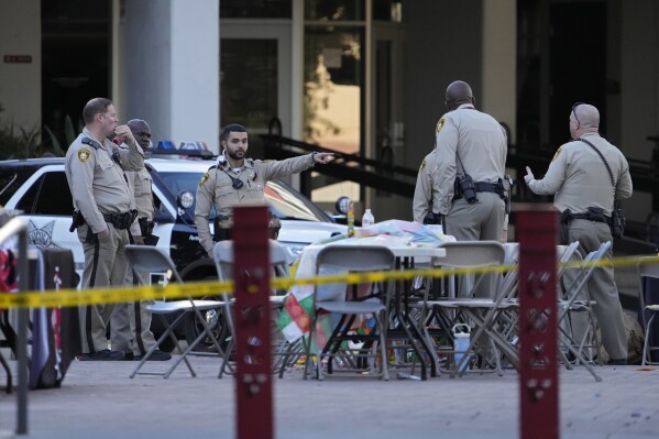 Las Vegas police stand near the scene of a shooting at the University of Nevada, Las Vegas, Thursday, Dec. 7, 2023, in Las Vegas. Terrified students and professors cowered in classrooms and dorms as a gunman roamed the floors of a campus building on Wednesday, killing several people and critically wounding another person before dying in a shootout with police. (AP Photo/John Locher)