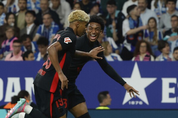 Lamine Yamal, del Barcelona, ​​a la izquierda, celebra con su compañero Alejandro Balde tras anotar el primer gol de su equipo durante un partido de la Liga española entre el Barcelona y el Espanyol en el Estadio Olímpico Lluis Companys en Barcelona, ​​España, el jueves 15 de mayo de 2025. (Foto AP/Joan Monfort)