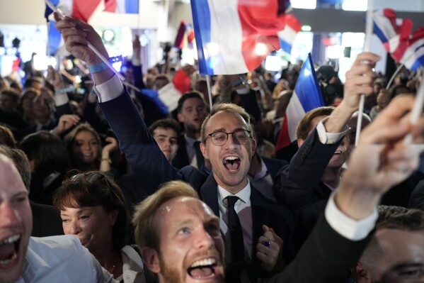 Apoiadores do Rally Nacional de extrema direita francês reagem na sede da noite eleitoral do partido em Paris, domingo, 9 de junho de 2024.  Os primeiros resultados das previsões da França colocam o partido de extrema-direita Reunião Nacional na liderança nas eleições da UE, de acordo com empresas de sondagens francesas.  (Foto AP/Louis Jolly)