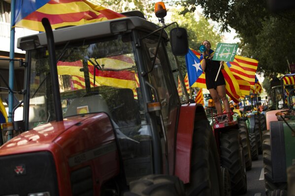 
              A woman with the estelada, or Catalonia independence flags, shouts slogans on top of parked tractors during a protest by farmers in Barcelona, Friday, Sept. 29, 2017. Authorities in Catalonia aim to ensure that a disputed referendum on independence from Spain will take place peacefully on Sunday despite a crackdown on the vote by the national government, the region's interior chief said. The small placard read: "Freedom". (AP Photo/Francisco Seco)
            