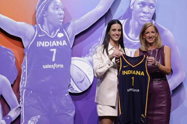 CORRECTS TO CAITLIN CLARK NOT CAITLYN CLARK - Iowa's Caitlin Clark, left, poses for a photo with WNBA commissioner Cathy Engelbert, right, after being selected first overall by the Indiana Fever during the first round of the WNBA basketball draft, Monday, April 15, 2024, in New York. (AP Photo/Adam Hunger)