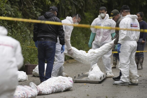 Forensics collect the wrapped bodies of victims of an avalanche that smothered their homes overnight, in El Naranjal, Colombia, Tuesday, July 18, 2023. (AP Photo/Fernando Vergara)