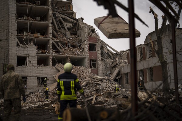 Firefighters work on a building that was partially destroyed after a Russian bombardment in Chernihiv, Ukraine, Wednesday, April 17, 2024. Three Russian missiles slammed into a downtown area of the northern Ukrainian city of Chernihiv on Wednesday, hitting an eight-floor apartment building and killing at least 17 people, authorities said. (AP Photo/Francisco Seco)