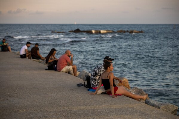 People sit on a breakwater near the beach in Barcelona, Spain, Friday, July 17, 2020. Health authorities are asking Barcelona's 5.5 million residents to reduce their socialization to a minimum and to stay at home as much as possible to stem the spread of the new coronavirus. (AP Photo/Emilio Morenatti)