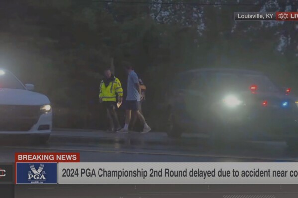 In this still image made from video provided by ESPN, Masters champion Scottie Scheffler is escorted by police after being handcuffed near Valhalla Golf Club, site of the PGA Championship golf tournament, early Friday, May 17, 2024. (ESPN via AP)
