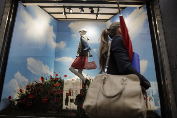 FILE - A woman walks past the Gucci store window at the Via Montenapoleone fashion district, during the Milan's fashion week in Milan, Italy, Friday, Sept. 25, 2020. The post-pandemic surge in global sales of luxury handbags, shoes and apparel is on pace to stall this year amid a creativity crisis and price hikes focused on the biggest spending customers. (AP Photo/Luca Bruno, File)