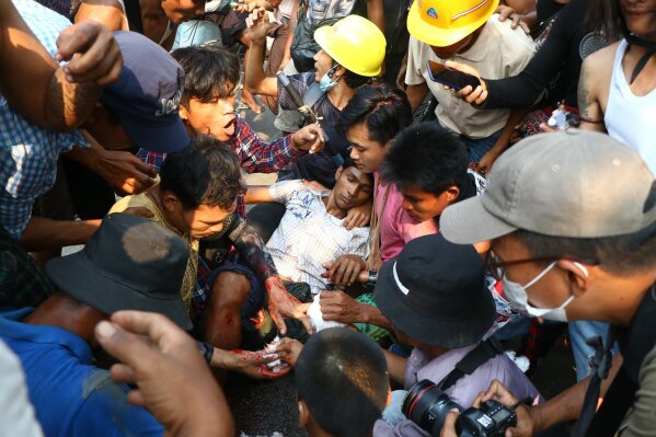 Anti-coup protesters surround an injured man in Hlaing Thar Yartownship in Yangon, Myanmar Sunday, March 14, 2021. A number of people were shot dead during protests in Myanmar's largest city on Sunday, as security forces continued their violent crackdown against dissent following last month's military coup. (AP Photo)