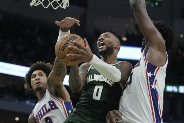 Milwaukee Bucks' Damian Lillard shoots between Philadelphia 76ers' Kelly Oubre Jr. and Joel Embiid during the second half of an NBA basketball game Thursday, Oct. 26, 2023, in Milwaukee. The Bucks won 118-117. (AP Photo/Morry Gash)