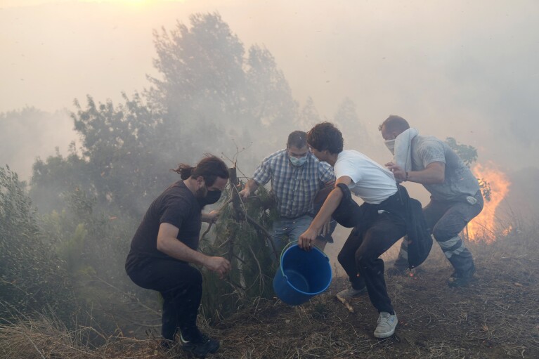 Local residents use buckets with water to try to slow down flames approaching their houses in Alcabideche, outside Lisbon, July 25, 2023. (AP Photo/Armando Franca)
