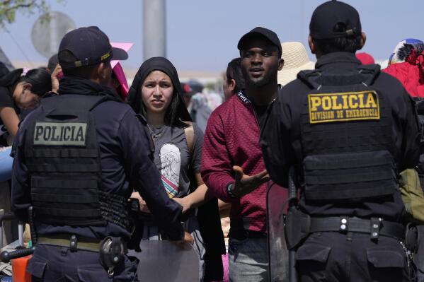 Venezuelan migrants speak with Peruvian police guarding the border with Chile in Tacna, Peru, Friday, April 28, 2023. A migration crisis at the border between Chile and Peru intensified Thursday as hundreds of people remained stranded, unable to cross into Peru. (AP Photo/Martin Mejia)