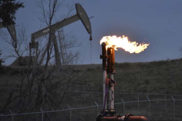 FILE - A flare burns at a well pad Aug. 26, 2021, near Watford City, N.D. American oil and natural gas wells, pipelines and compressors are spewing three times the amount of the potent heat-trapping gas methane as the government thinks, a new comprehensive study calculates. (AP Photo/Matthew Brown, File)