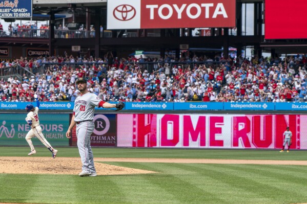 Philadelphia Phillies' Alec Bohm, back left, rounds the bases after hitting a three-run home run as Washington Nationals relief pitcher Tanner Rainey (21) gets a new ball during the eighth inning of a baseball game, Sunday, May 19, 2024, in Philadelphia. (AP Photo/Chris Szagola)