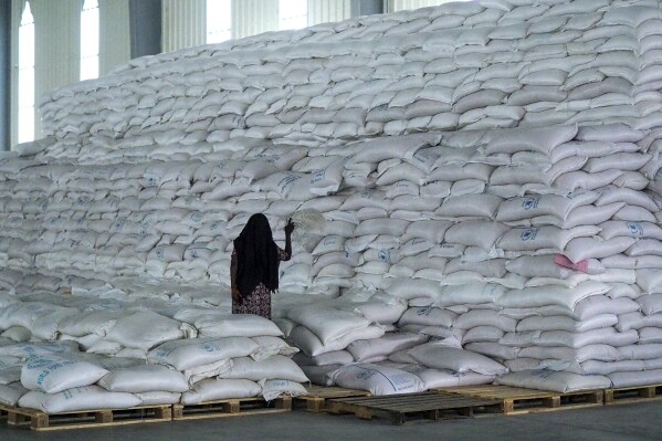 FILE - A worker walks next to a pile of sacks of food earmarked for the Tigray and Afar regions in a warehouse of the World Food Programme (WFP) in Semera, the regional capital for the Afar region, in Semera, Ethiopia, Feb. 21, 2022. Only a small fraction of needy people in Ethiopia’s northern Tigray region are receiving food aid, according to an aid memo seen by The Associated Press, more than one month after aid agencies resumed deliveries of grain following a lengthy pause over theft. (AP Photo, File)