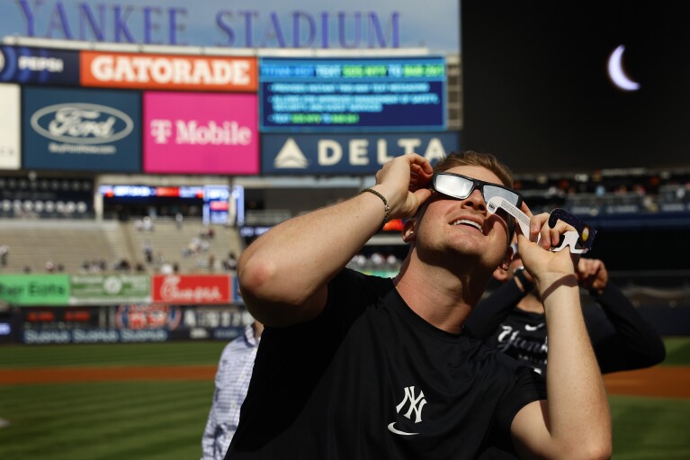 New York Yankees' Clarke Schmidt watches the eclipse from Yankee Stadium, Monday, April 8, 2024 in New York. (AP Photo/Noah K. Murray)