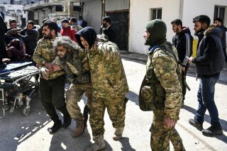 In this photo taken on Sunday, March 1, 2020, Turkey-backed opposition fighters help a fellow fighter wounded in fighting with Syrian government forces and their allies in Sarmin, south of Idlib, S...