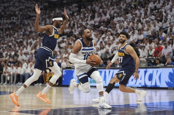 Minnesota Timberwolves guard Mike Conley (10) works toward the basket as Denver Nuggets forward Justin Holiday, left, and guard Jamal Murray (27) defend during the first half of Game 4 of an NBA basketball second-round playoff series, Sunday, May 12, 2024, in Minneapolis. (AP Photo/Abbie Parr)