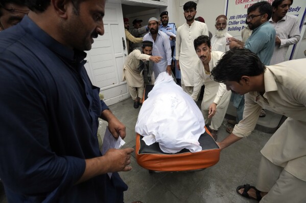 Relatives carry the body of a man killed after a wall collapse due to monsoon rains into an ambulance at PIMS hospital in Islamabad, Pakistan, Wednesday, July 19, 2023. Multiple workers were killed early Wednesday after a portion of the outer wall of a sprawling compound collapsed after being weakened by rains near an under-construction bridge on the outskirts of Pakistan's capital, Islamabad, police and rescue officials said. (AP Photo/Rahmat Gul)