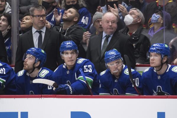 New Vancouver Canucks head coach Bruce Boudreau, back right, and assistant coach Scott Walker, back left, stand on the bench behind, from left to right, Tyler Motte, Bo Horvat, Tanner Pearson and Vasily Podkolzin, of Russia, during first-period NHL hockey game action against the Los Angeles Kings in Vancouver, British Columbia, Monday, Dec. 6, 2021. Darryl Dyck/The Canadian Press via AP)