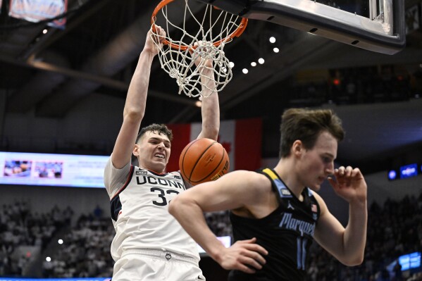 UConn center Donovan Clingan dunks behind Marquette guard Tyler Kolek (11) in the first half of an NCAA college basketball game, Saturday, Feb. 17, 2024, in Hartford, Conn. (AP Photo/Jessica Hill)